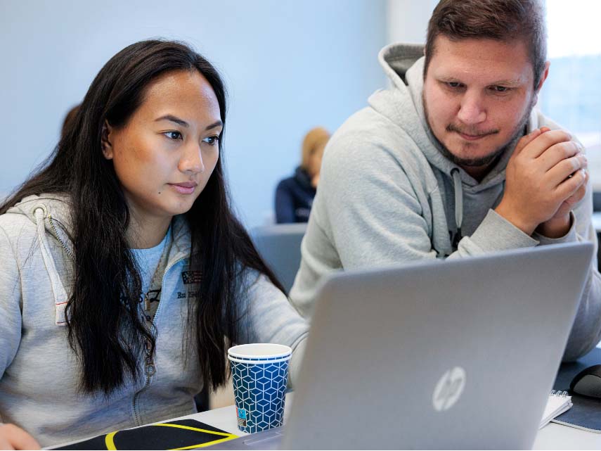 Två elever tittar på en datorskärm i ett klassrum.