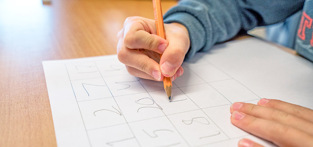 Barnhand skriver siffror. Foto: Hans Wretling