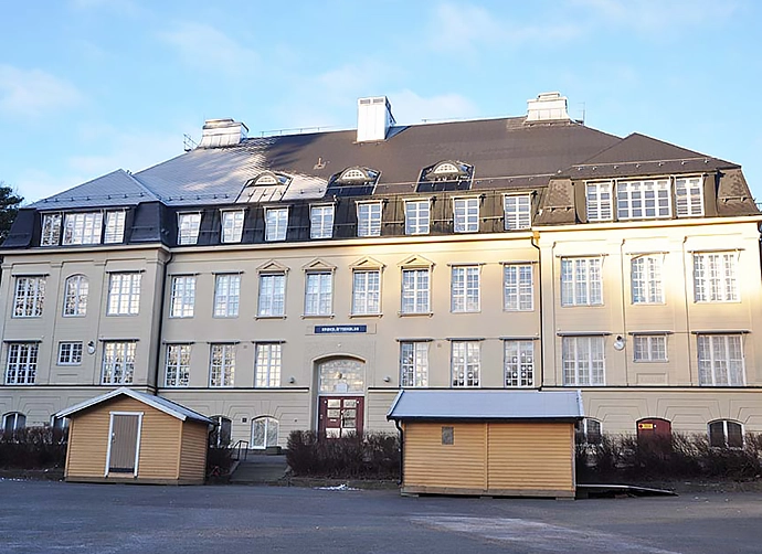 skolbyggnaden med skolgård och förråd i förgrund