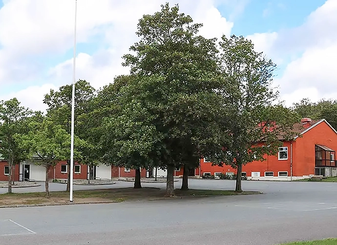 röd skolbyggnad med grönskade träd i förgrunden
