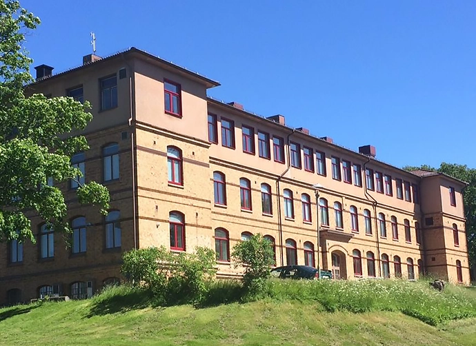 skolbyggnad i gult tegel på grön kulle