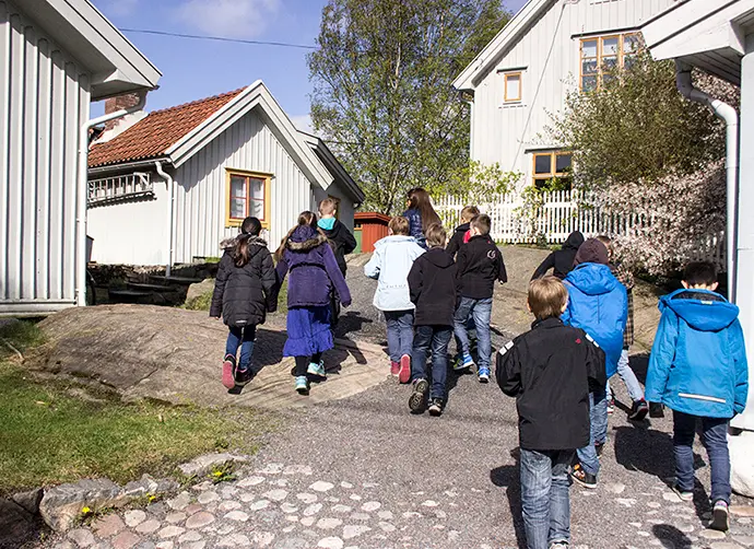 En grupp barn går bland gamla trähus.