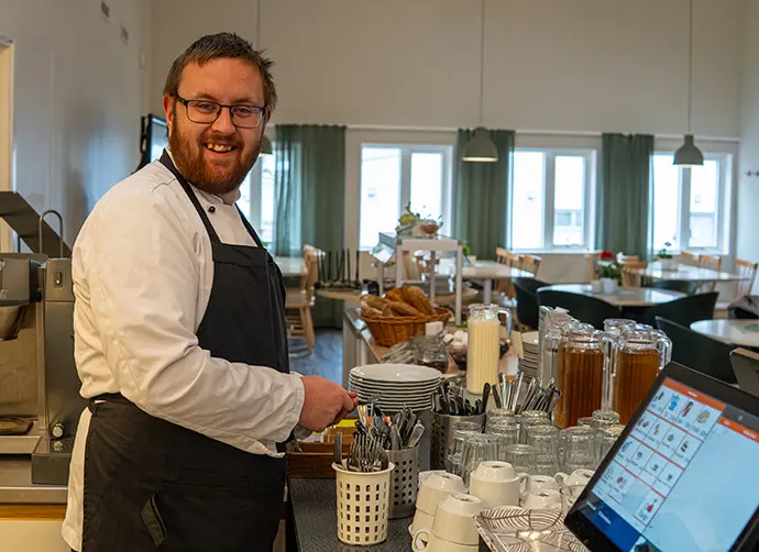 Elev arbetar med servering och förberedelser i restaurangmiljö.