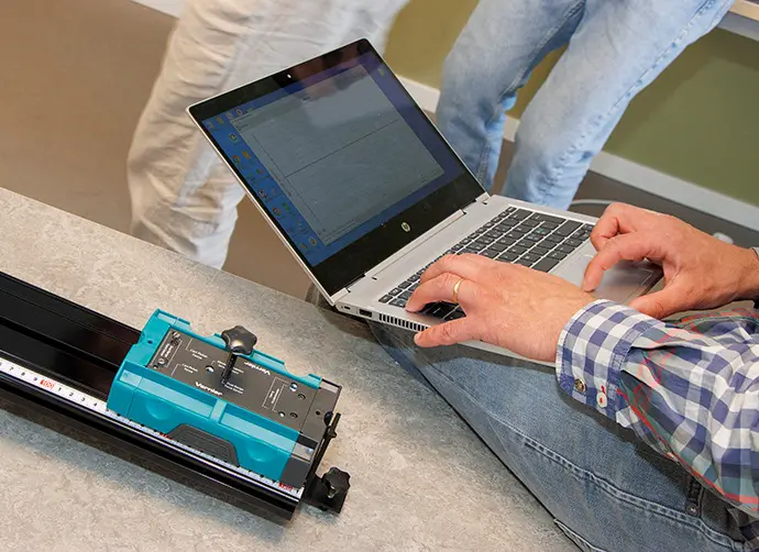Närbild på arbete vid laptop med teknisk utrustning och mätinstrument på bordet.