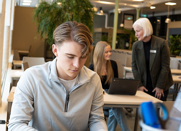 Elev arbetar fokuserat vid laptop i klassrum.