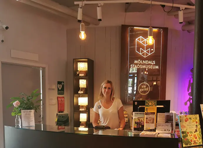 En kvinna står bakom en receptionsdisk. 