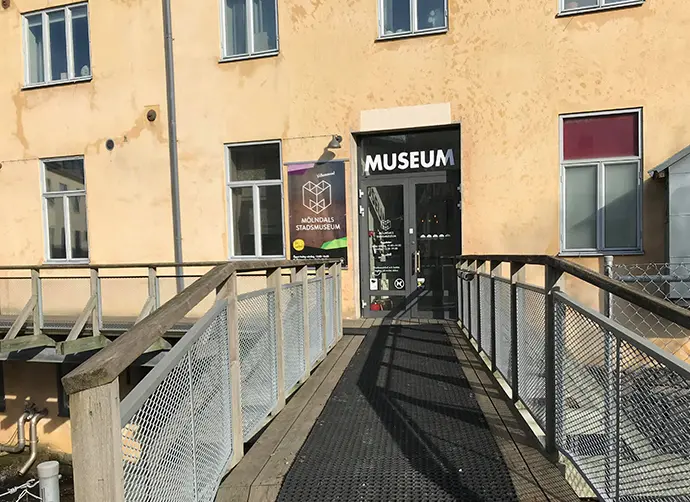 En entré till ett beigt hus. En bro leder fram till entré. 