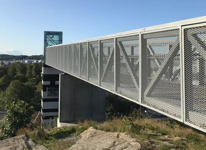 Utomhushissen Kråkfoten som går upp till Störtfjället. Det går en modernistisk gångbro med ett metallnät ut till hissen från berget.