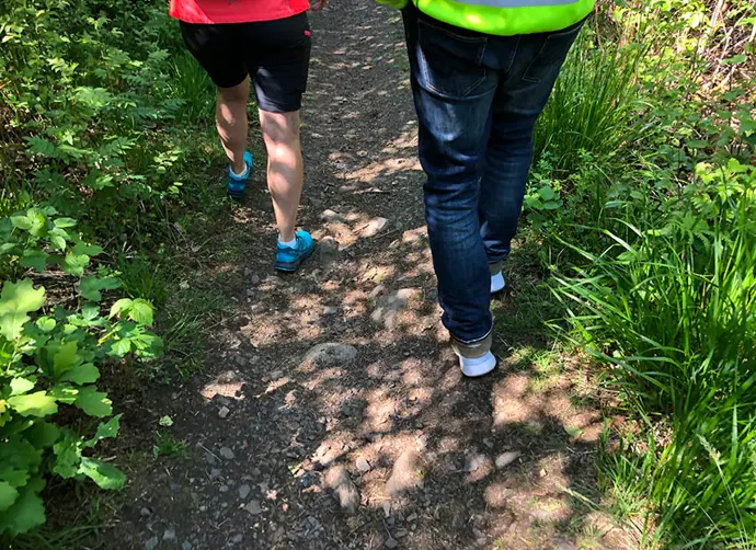 Två personers ben ses när de promenerar längs med Bohusleden.