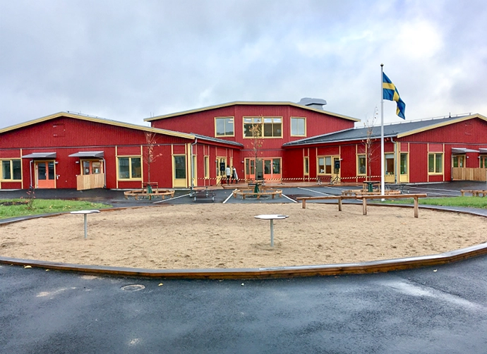 röd förskola med sandlåda i förgrunden