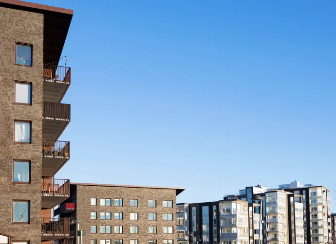 Bostadshus i Stallbacken. Tegelbeklädda bostadsbyggnader med balkonger och fönster mot en blå himmel.