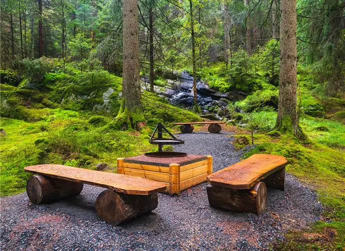 Grillplats i ett skogsparti med ett vattenfall i bakgrunden.