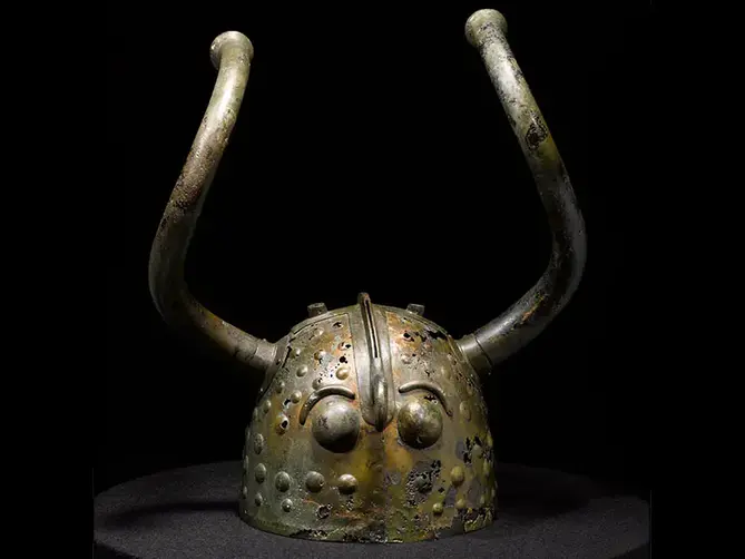 En hjälm i brons med långa vridna horn. 