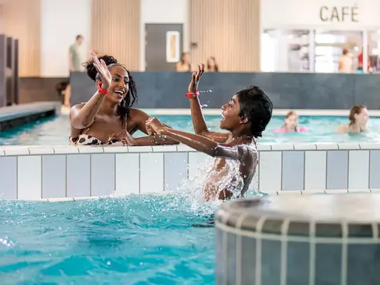 Mor och son gör high five i Stora lekbassängen i Åbybadet.