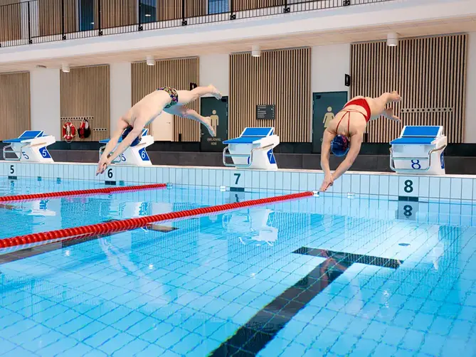 Två simmare startar från startpall i 50-metersbassängen i Åbybadet.