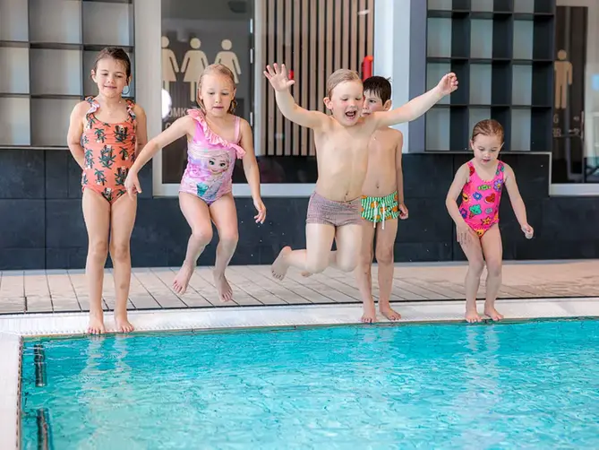 Barn som hoppar från kanten i varmbassängen i Åbybadet.