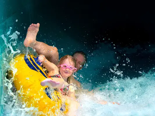 Far och dotter på dubbelring i den gröna vattenrutschbanan i Åbybadet.