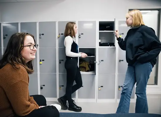 Tre elever står vid skåp och samtalar i skolan