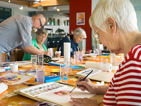Äldre kvinnor som målar vid ett bord