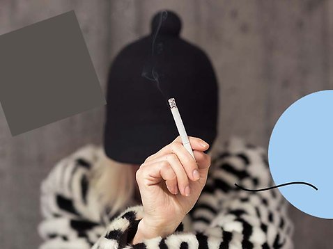 En hand som håller i cigarett. I bakgrunden syns personen som håller i cigaretten, med en mössa över huvudet.