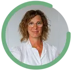 Petra Hall bär en vit blus och glasögon. Hon har lockigt hår och ett varmt leende mot kameran.