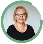 Marie Karlsson bär glasögon och svart tröja. Hon har kort, lockigt blont hår och ett vänligt uttryck.