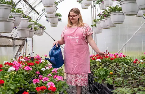 Elev med rosa förkläde vattnar blommorna