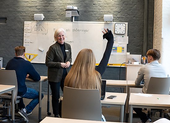 Elev räcker upp handen under lektion.