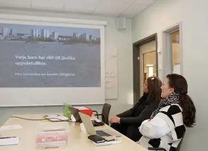 två rektorer sitter och tittar på en presentation på förskolan