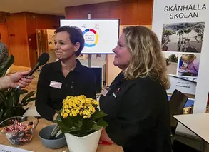 två pedagoger blir intervjuade vid ett bord med en gul blomma