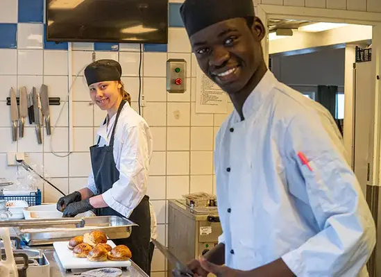 Två elever arbetar i kök och förbereder mat.