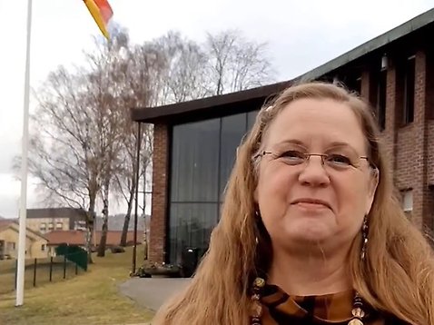 En kvinna ler mot kameran framför Svenska kyrkans kontor.