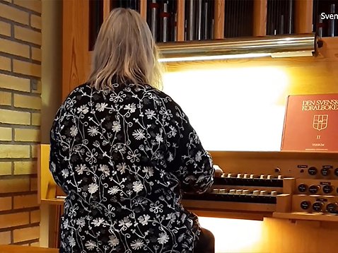 En kvinna spelar på orgel inuti kyrkan.
