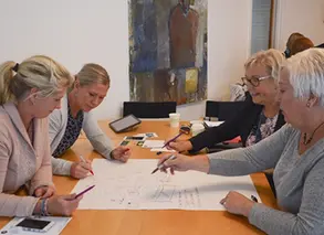 pedagoger sitter vid ett bord och skriver på ett stort papper